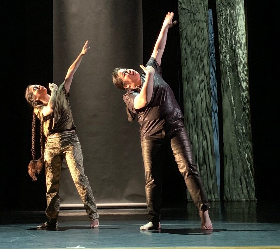 Two dancers with left arm over head and looking up