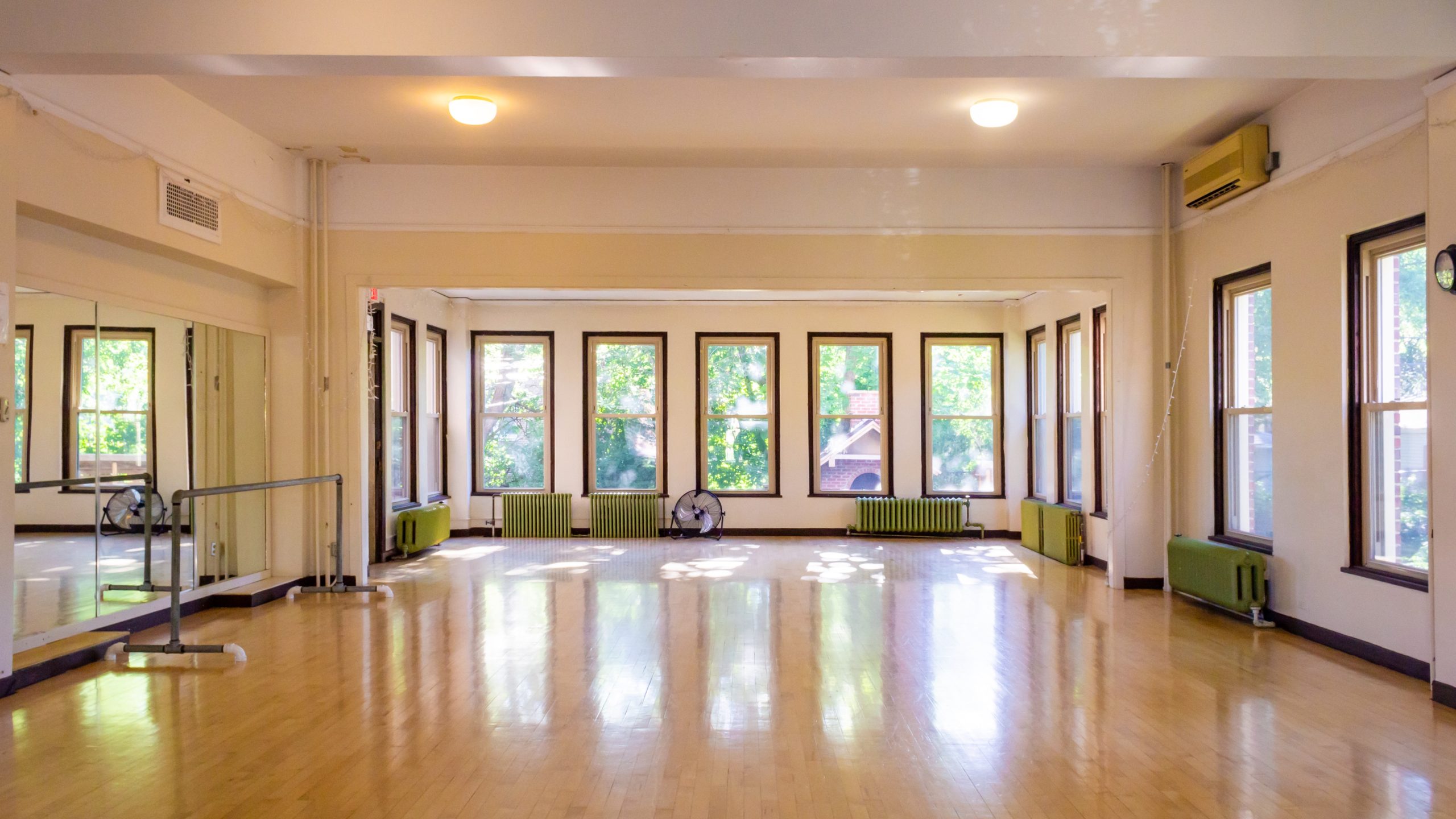 Studio with wooden floors, windows, and a mirrored wall