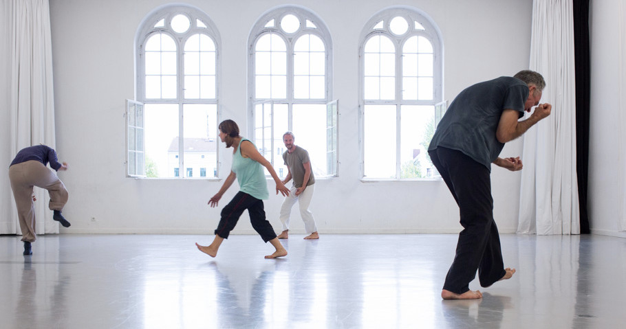 four bodies captured in motion throughout a large studio